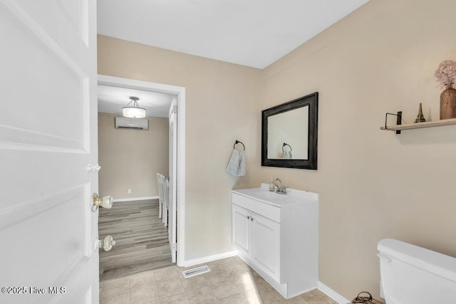 bathroom featuring vanity, a wall mounted AC, and toilet