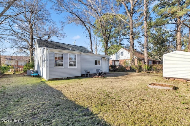 rear view of property with a yard and a storage unit