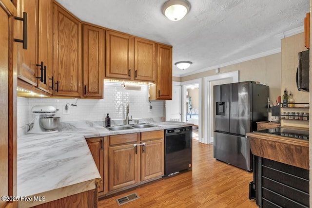 kitchen featuring sink, crown molding, light hardwood / wood-style flooring, stainless steel fridge, and dishwasher