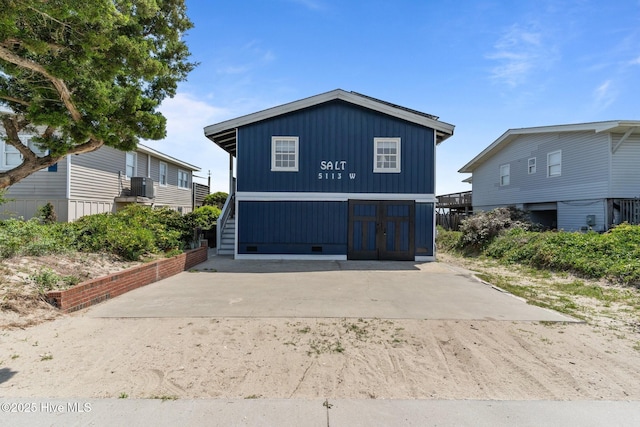 view of front facade featuring central AC, stairway, board and batten siding, and crawl space