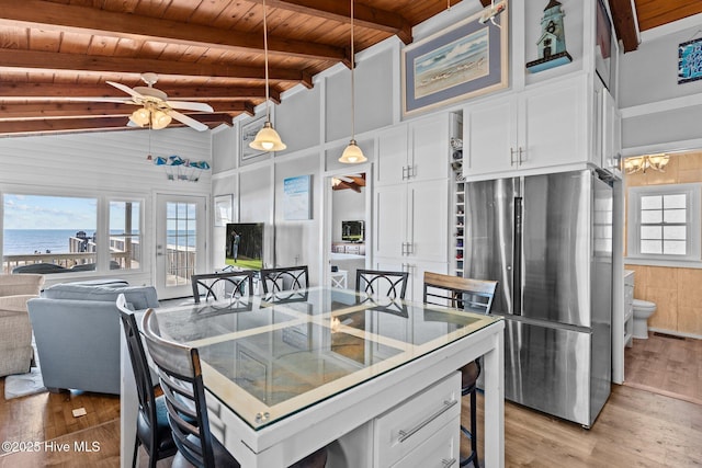 kitchen featuring stainless steel fridge, white cabinetry, a water view, decorative light fixtures, and wooden ceiling