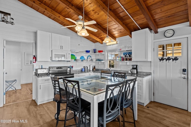 kitchen with light wood finished floors, wooden ceiling, lofted ceiling with beams, open shelves, and white microwave
