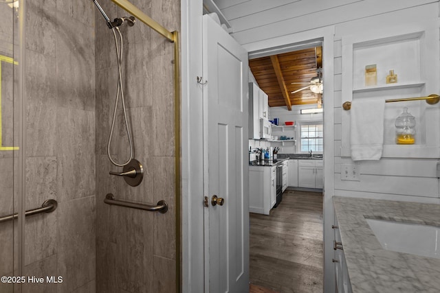 bathroom featuring a tile shower, wood-type flooring, vanity, wooden ceiling, and beam ceiling