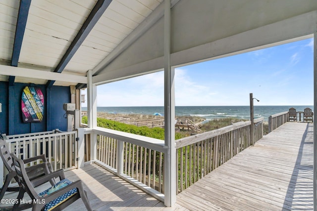 wooden deck with a water view and a view of the beach