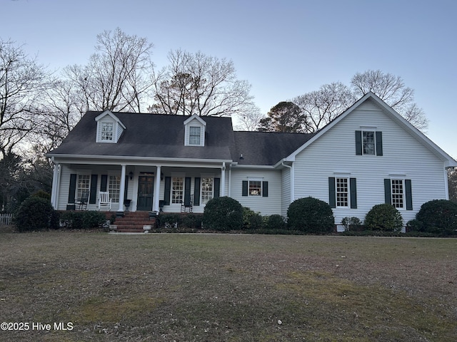 cape cod house with a porch and a front lawn