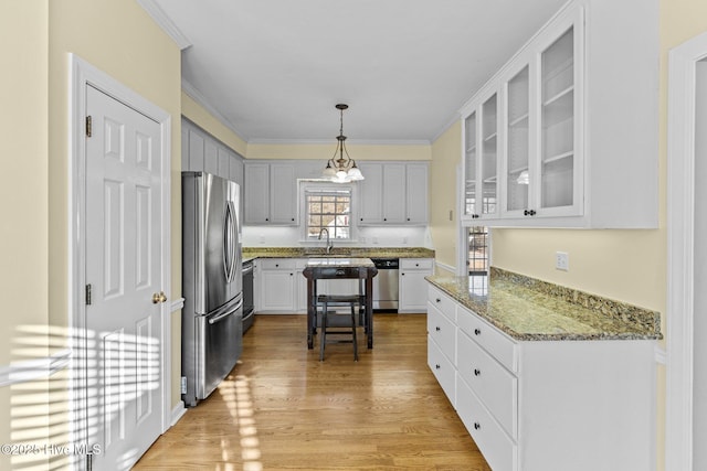 kitchen featuring sink, white cabinetry, decorative light fixtures, light wood-type flooring, and stainless steel appliances