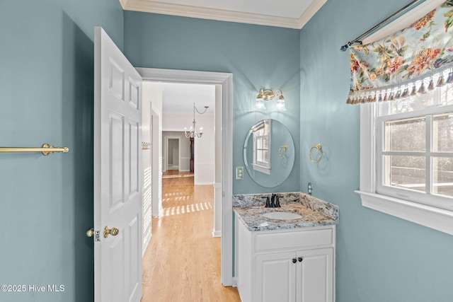 bathroom with vanity, wood-type flooring, ornamental molding, and a chandelier