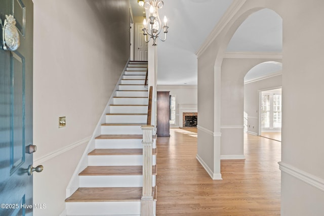 1985 Den Tree Ct, New Bern, NC 28562 - foyer with crown molding, stairs, arched walkways, light wood-style floors, and a fireplace