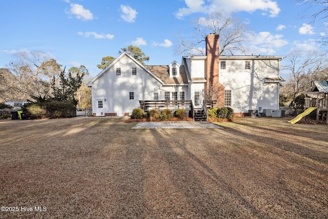 1985 Den Tree Ct, New Bern, NC 28562 - rear view of property featuring central air condition unit, a chimney, a deck, and a playground