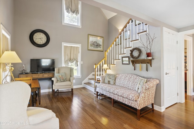 living room with a high ceiling, a wealth of natural light, and dark wood-type flooring