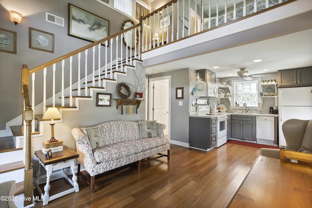 living room featuring ceiling fan, sink, a towering ceiling, and dark hardwood / wood-style floors