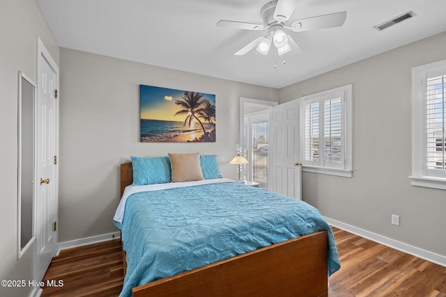 bedroom featuring ceiling fan, dark wood-type flooring, and multiple windows