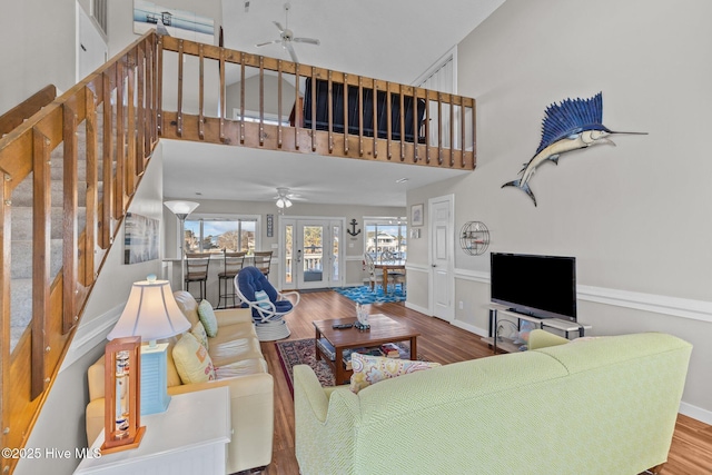 living room with french doors, a towering ceiling, ceiling fan, and hardwood / wood-style floors