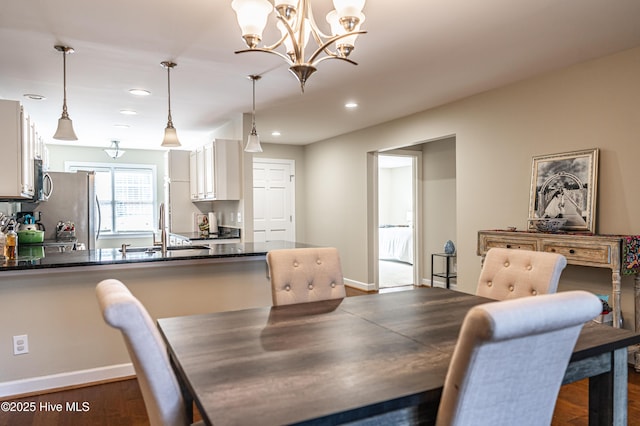 dining space with sink, dark hardwood / wood-style flooring, and a chandelier