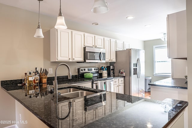 kitchen featuring kitchen peninsula, pendant lighting, white cabinets, appliances with stainless steel finishes, and sink