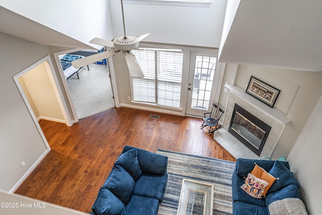 living room with a tiled fireplace and dark hardwood / wood-style flooring