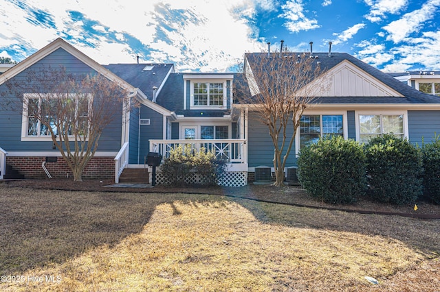 view of front of home with central AC unit and a front yard