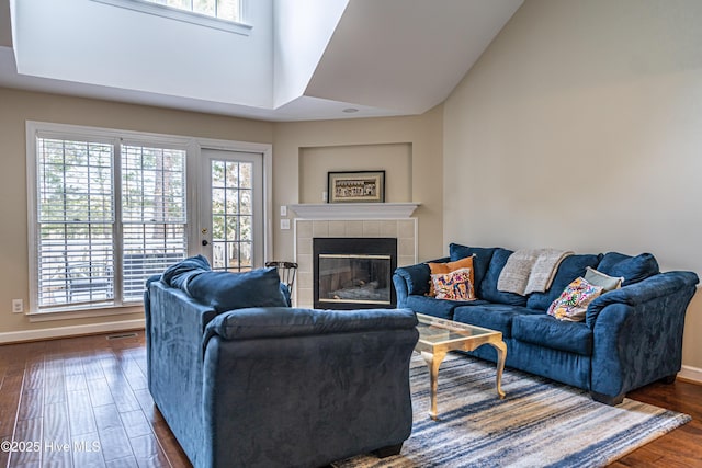 living room with a towering ceiling, a fireplace, and dark hardwood / wood-style floors