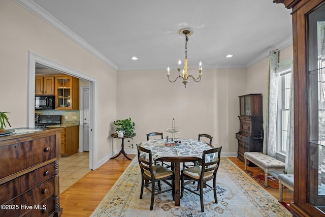 dining room with crown molding, sink, a chandelier, and light hardwood / wood-style floors