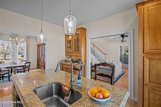 kitchen featuring light stone countertops, sink, pendant lighting, and light hardwood / wood-style flooring