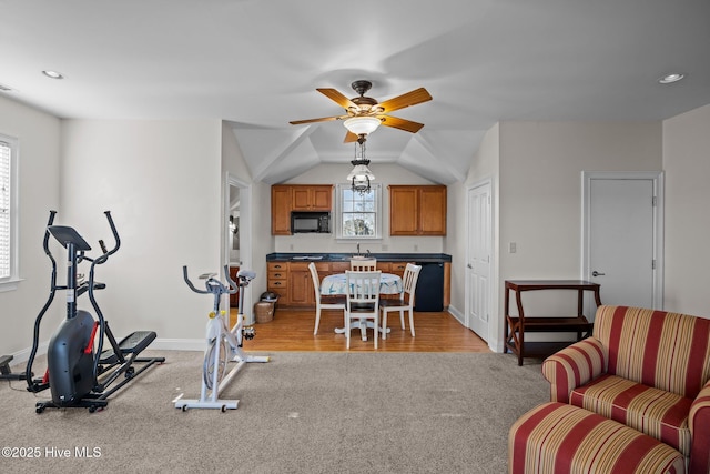 exercise room featuring ceiling fan, vaulted ceiling, and light carpet