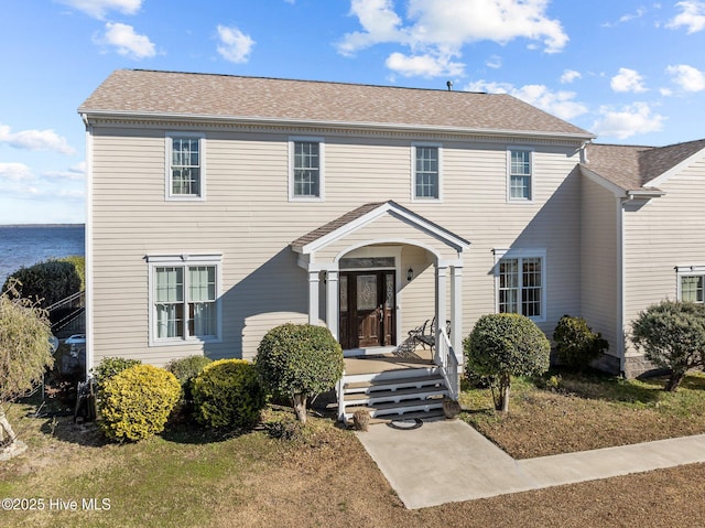 colonial house with a water view and a front lawn