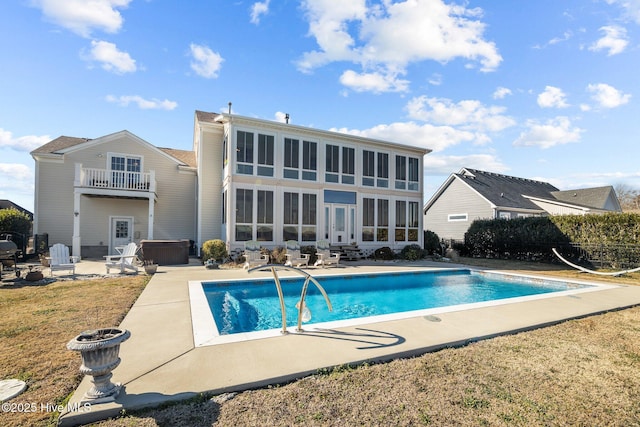 back of property with a pool with hot tub, a yard, a patio area, and a balcony