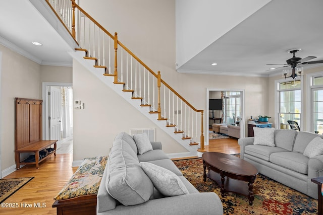 living room featuring ornamental molding, a towering ceiling, and light hardwood / wood-style floors