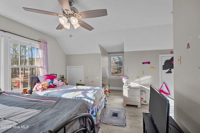 bedroom with ceiling fan, light hardwood / wood-style floors, and vaulted ceiling