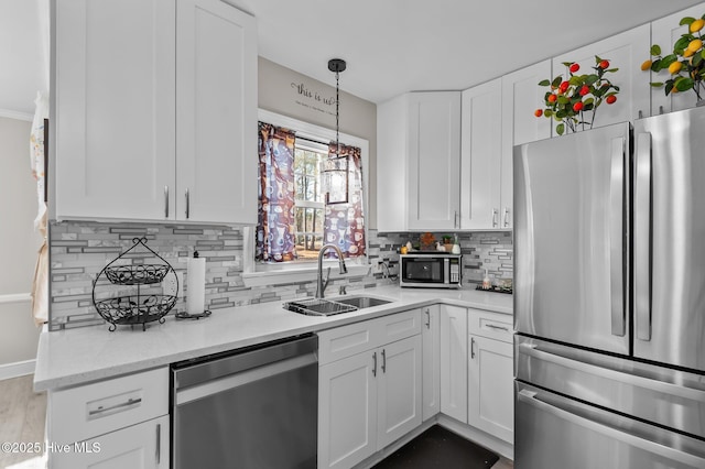 kitchen with white cabinets, appliances with stainless steel finishes, decorative light fixtures, tasteful backsplash, and sink