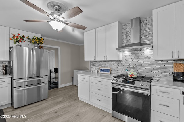 kitchen with wall chimney exhaust hood, white cabinetry, decorative backsplash, and appliances with stainless steel finishes