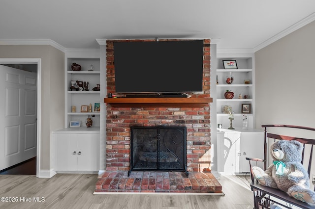 living room with a fireplace, built in features, hardwood / wood-style flooring, and crown molding