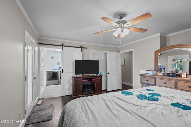 bedroom with crown molding, washing machine and clothes dryer, a barn door, dark hardwood / wood-style flooring, and ceiling fan