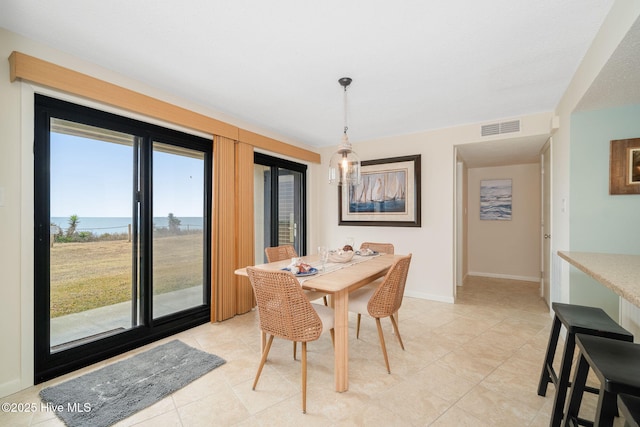 dining area featuring light tile patterned floors and a water view