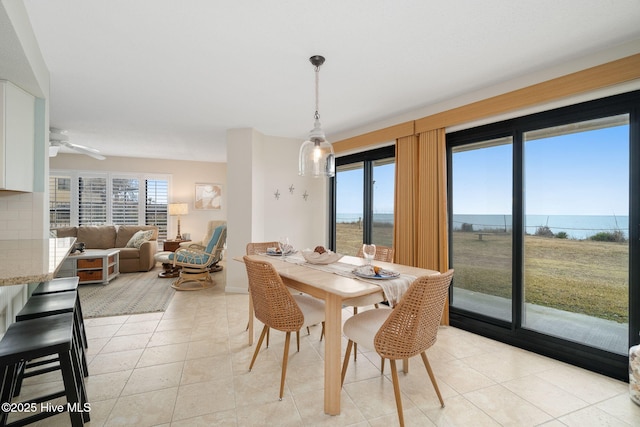 dining area featuring a wealth of natural light, ceiling fan, light tile patterned floors, and a water view