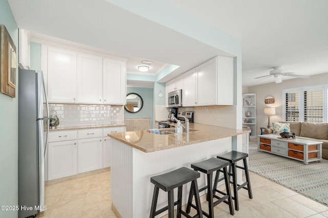 kitchen featuring stainless steel appliances, white cabinetry, backsplash, and kitchen peninsula