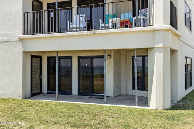 rear view of property featuring a yard and a balcony