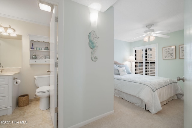 carpeted bedroom featuring ensuite bath, ceiling fan, and sink