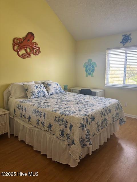 bedroom with a textured ceiling, wood-type flooring, and lofted ceiling