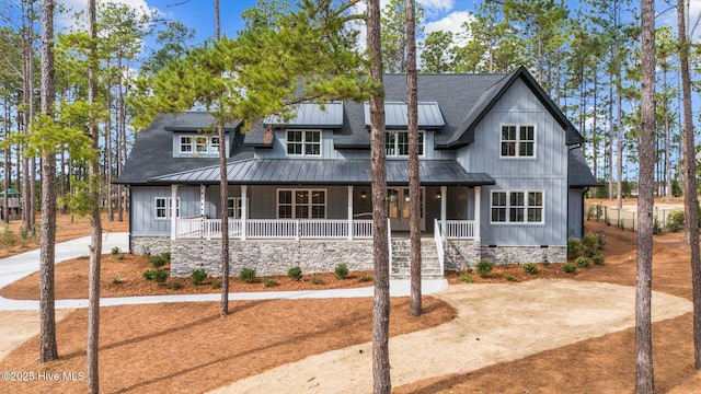 modern farmhouse with driveway, metal roof, a porch, and board and batten siding