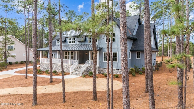 view of front of home with a shingled roof, covered porch, board and batten siding, a standing seam roof, and metal roof