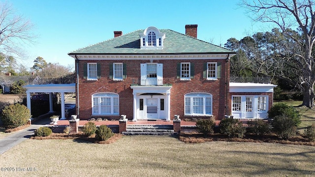 colonial-style house featuring a front yard and a carport