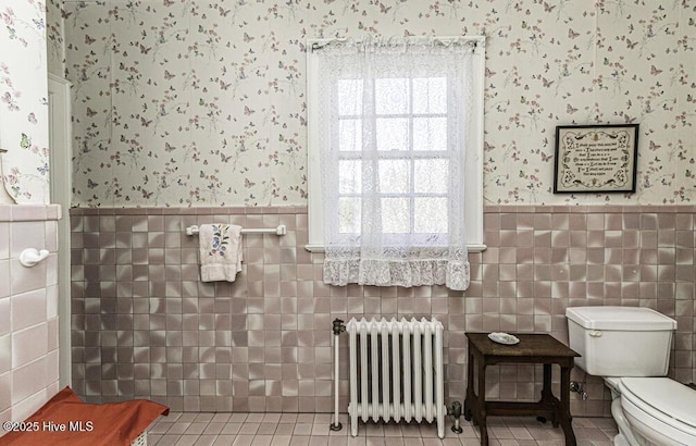 bathroom featuring radiator, toilet, tile patterned flooring, and tile walls