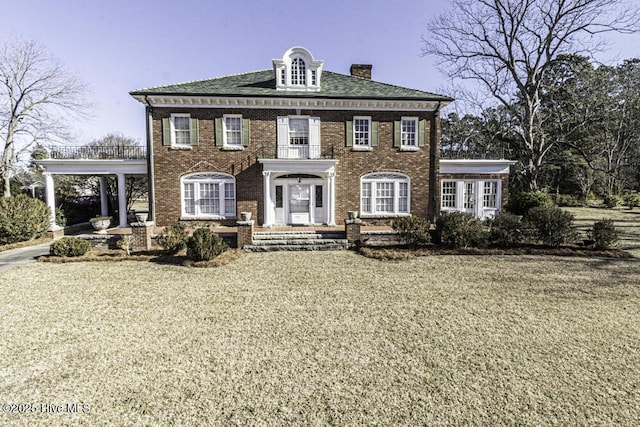 colonial house featuring a front yard and a carport