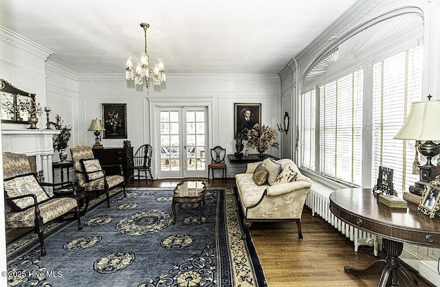 living room with french doors, a chandelier, ornamental molding, and hardwood / wood-style flooring