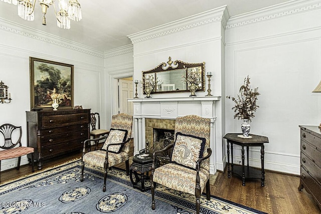 sitting room featuring dark hardwood / wood-style flooring, crown molding, a fireplace, and a chandelier