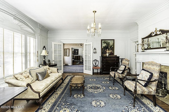 living room with hardwood / wood-style flooring, a notable chandelier, a fireplace, french doors, and crown molding