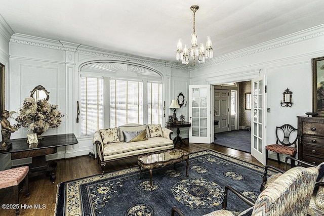 living room featuring dark hardwood / wood-style floors, crown molding, french doors, and a notable chandelier