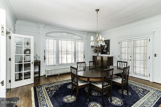 dining space featuring radiator heating unit, dark hardwood / wood-style flooring, french doors, ornamental molding, and a notable chandelier