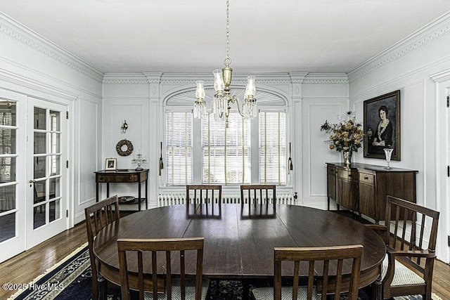 dining area featuring french doors, an inviting chandelier, ornamental molding, and hardwood / wood-style flooring